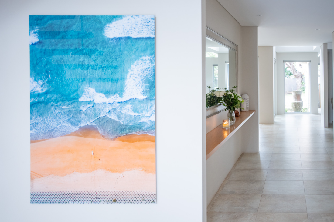 A large aerial beach print hanging in a white hallway